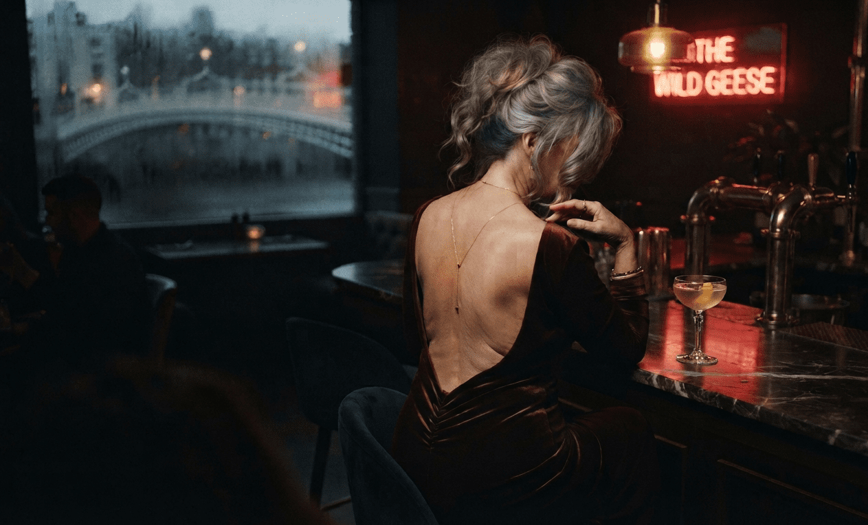 Refined mature woman at a Dublin lounge bar at night, backless gown seen from behind, granny dating