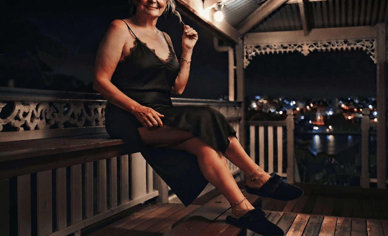 Mature woman relaxing on a Queenslander verandah at night above the river, granny dating Brisbane suburbs